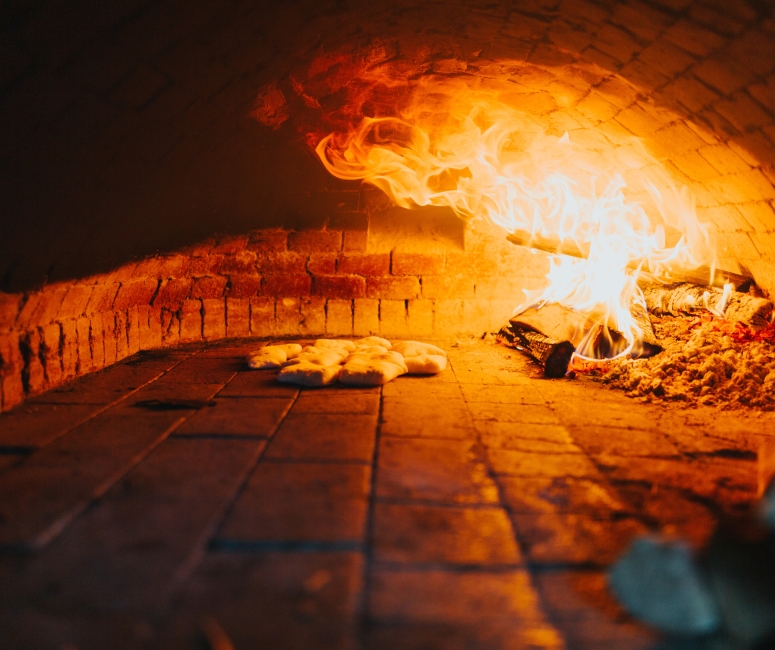 A closeup view of a wood fire oven baking some bread at Tar & Roses