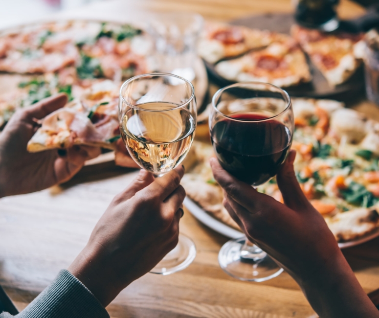 Two people enjoying some pizza and wine
